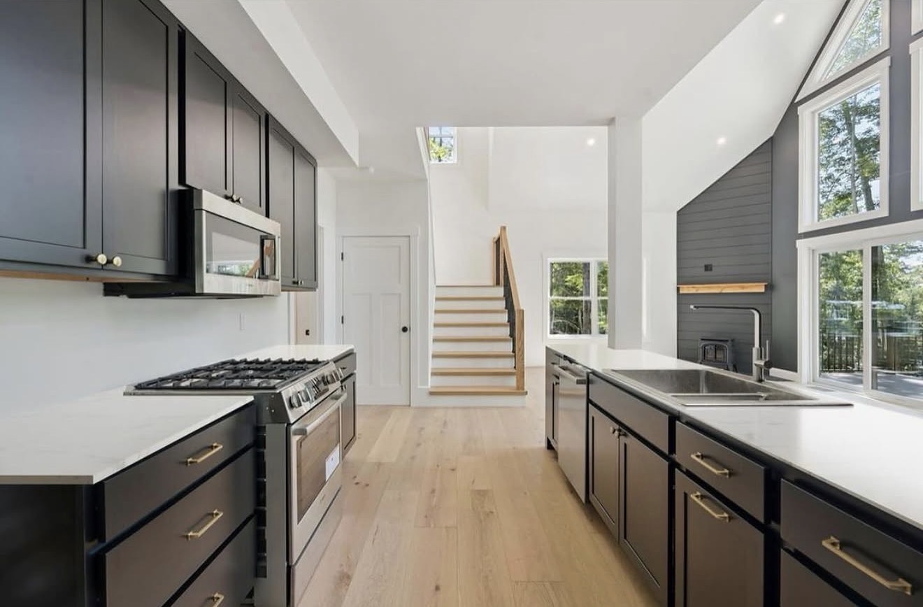 Custom kitchen remodel with dark navy cabinetry, brass hardware, pro range, and white oak floors
